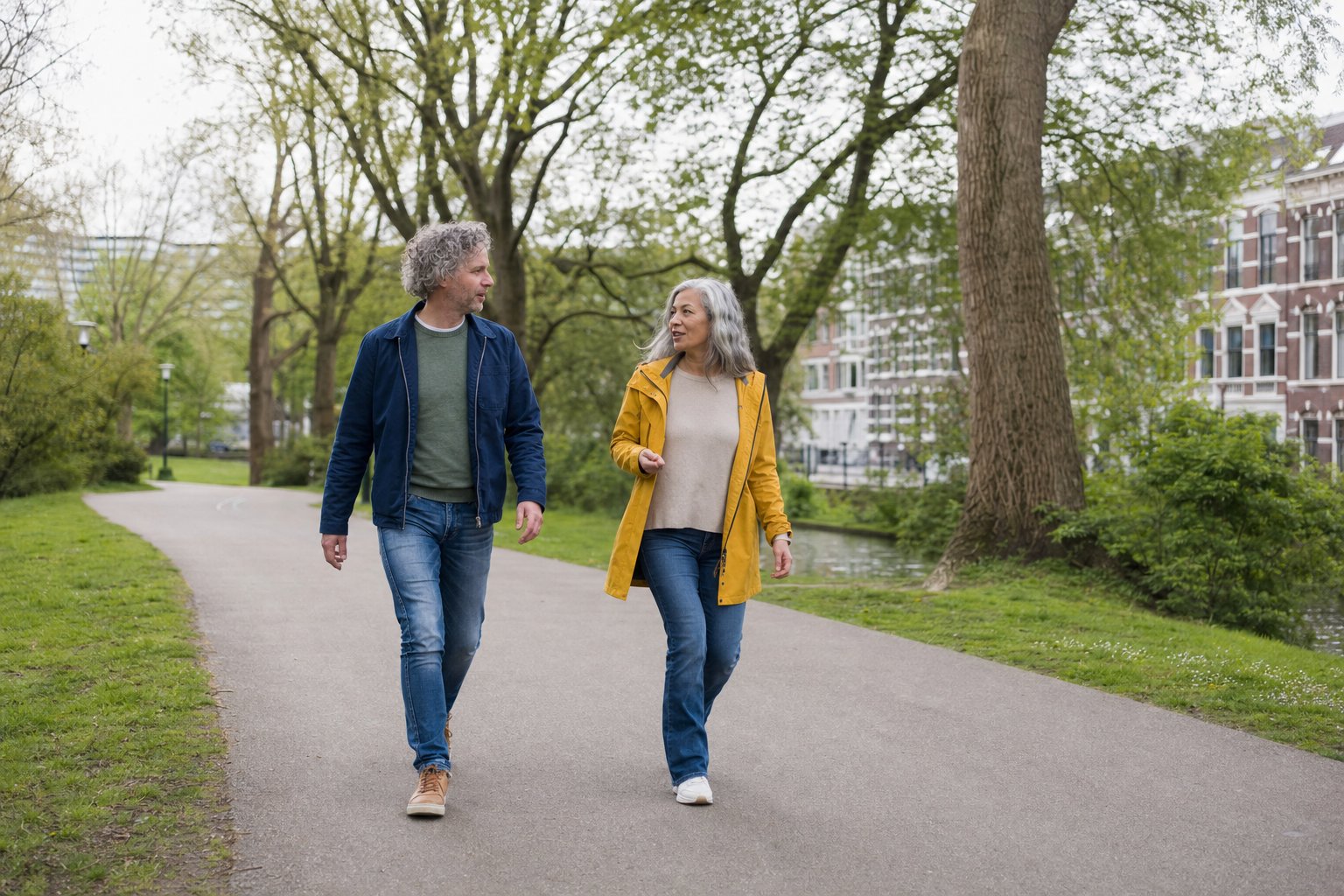 Twee volwassenen wandelen pratend door een groen stadspark